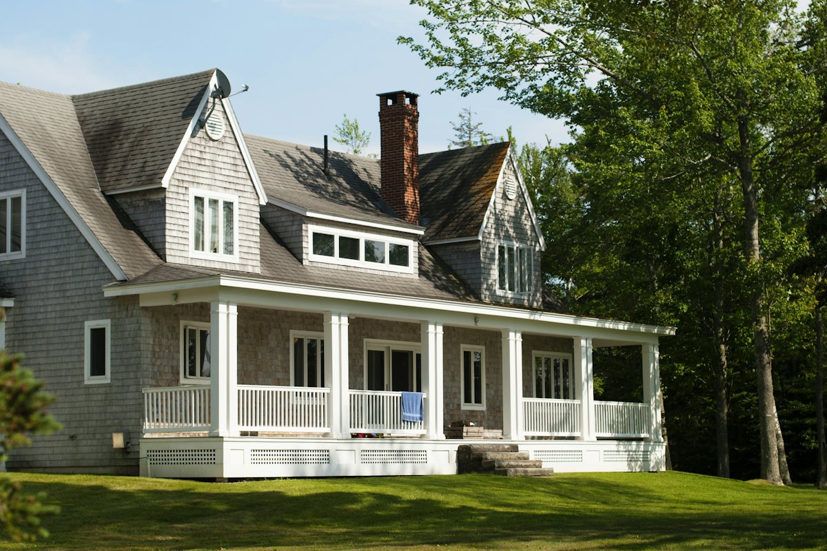 Shingle-style home with a wraparound porch